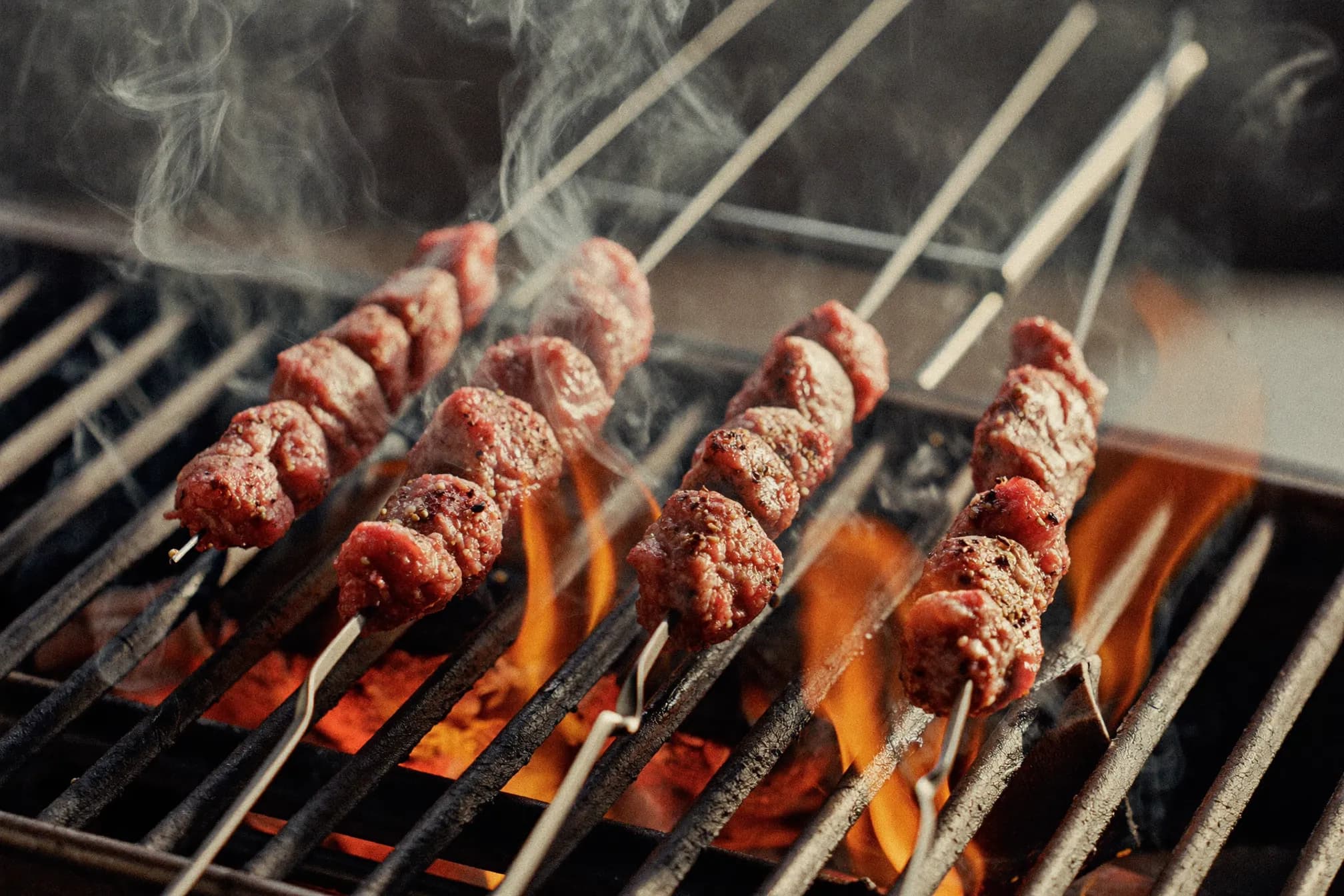 Adana skewers on a firing grill with flame licks